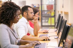 Multiracial group of students training in computer class.