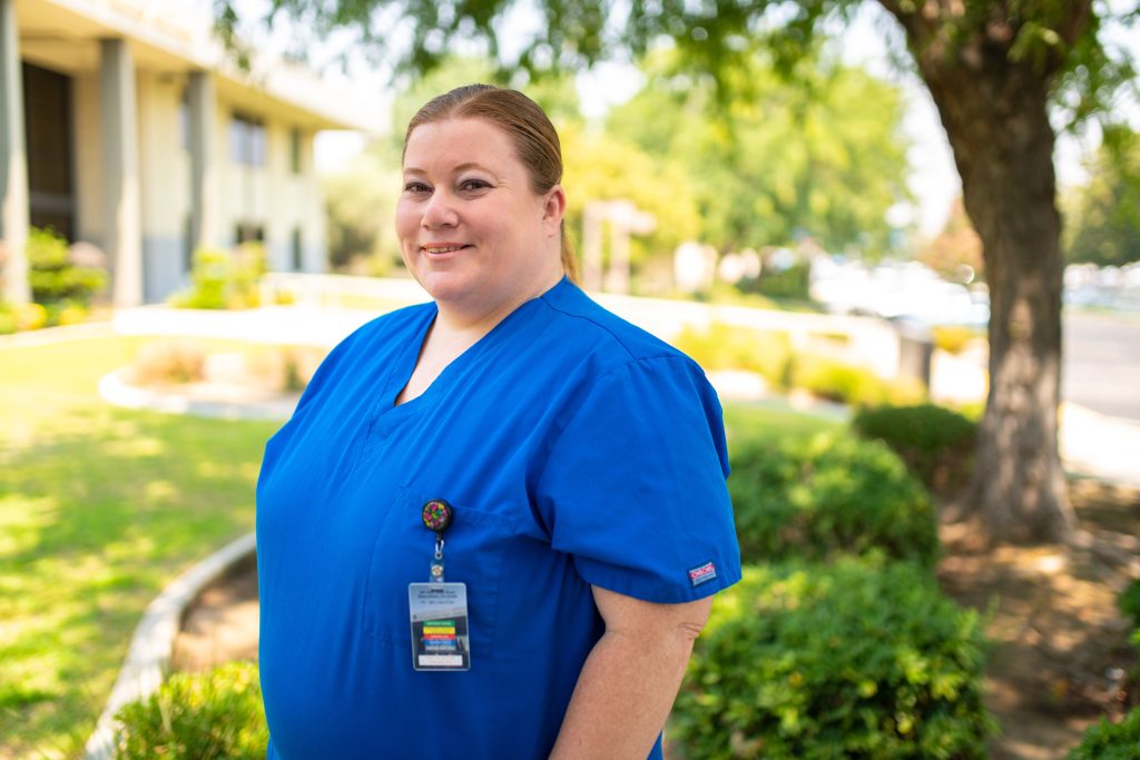 Margaret Martinez, a smiling woman in dark blue scrubs, who used adult school classes to earn her high school diploma.