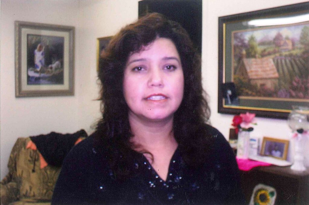 Maria L. Garcia smiles for the camera in her home, where she keeps up with classwork with a donated chromebook.