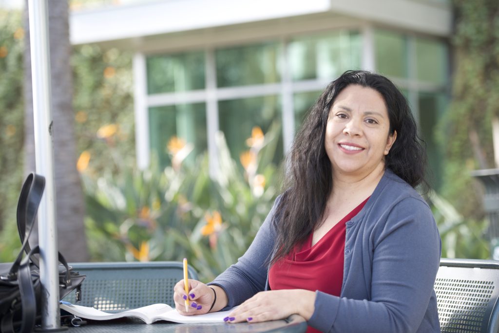 Berta Torres sits at an outdoor table doing school work.