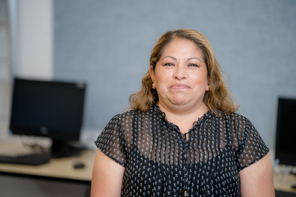 Francisca Juarez, a woman with dark hair with light brown highlights and a polka dot black blouse, smiles for the camera.