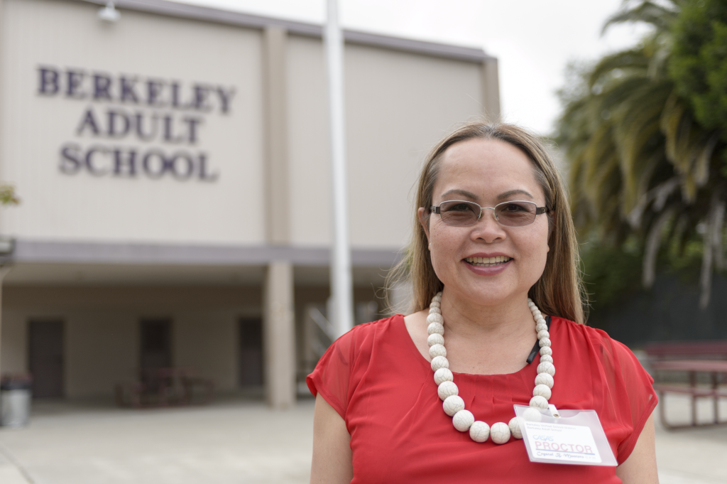 From ESL to Giving Back: A woman stands in front of the Berkeley Adult School. She is smiling at the camera.