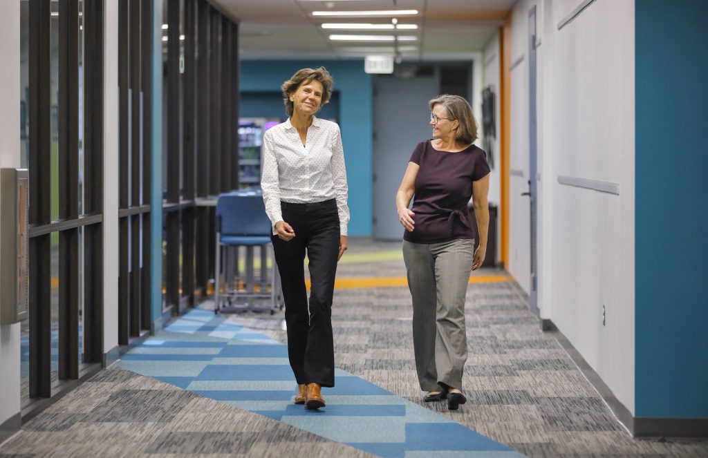 Ute Maschke, left, and Kim Bellaart, at right, walk along a corridor at Foothills Adult Education Center. 