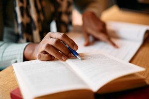 Close-up of African American female student learning from books in a library.