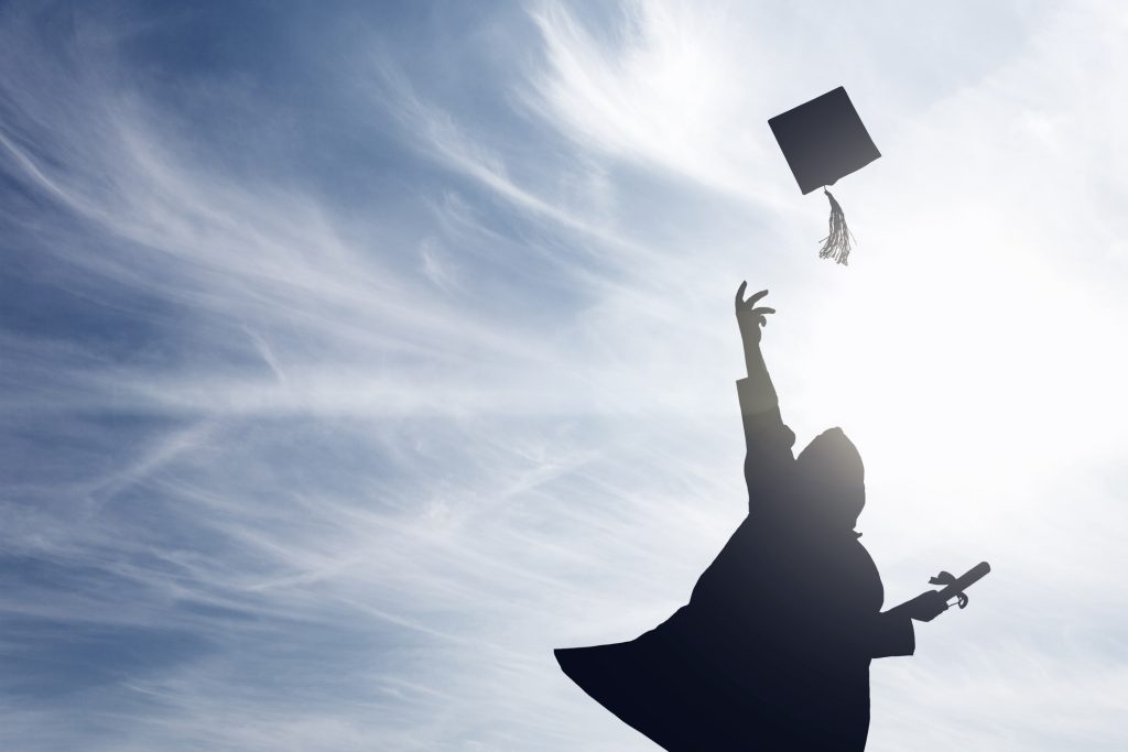 Graduate students tossing up hats over blue sky