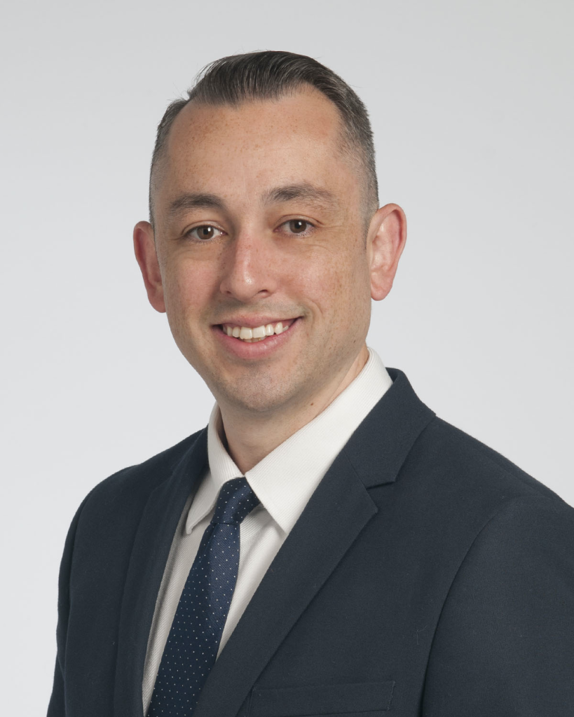 A professional headshot of Dr. Cesar Pillar, a man with close cropped hair in a suit and tie.