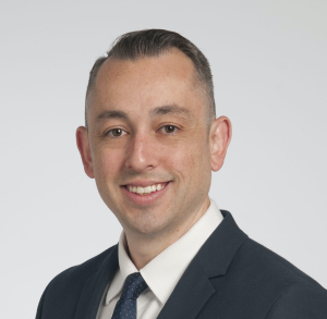 A professional headshot of Dr. Cesar Pillar, a man with close cropped hair in a suit and tie.