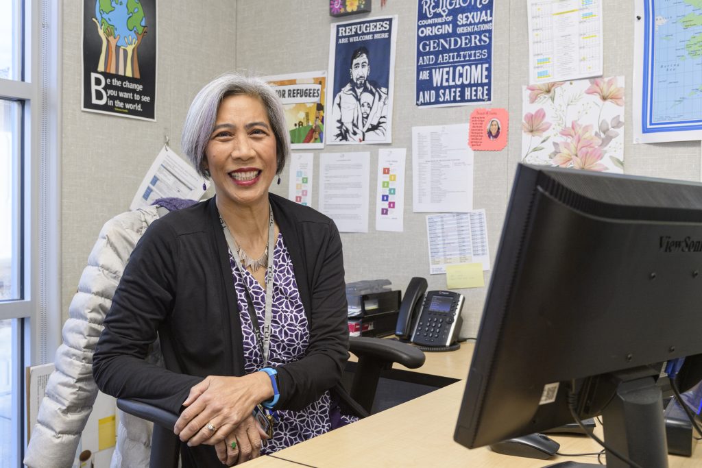 Johanna Lee, an Asian woman with a short gray bob, a purple blouse,and a black blazer sits at her office desk.