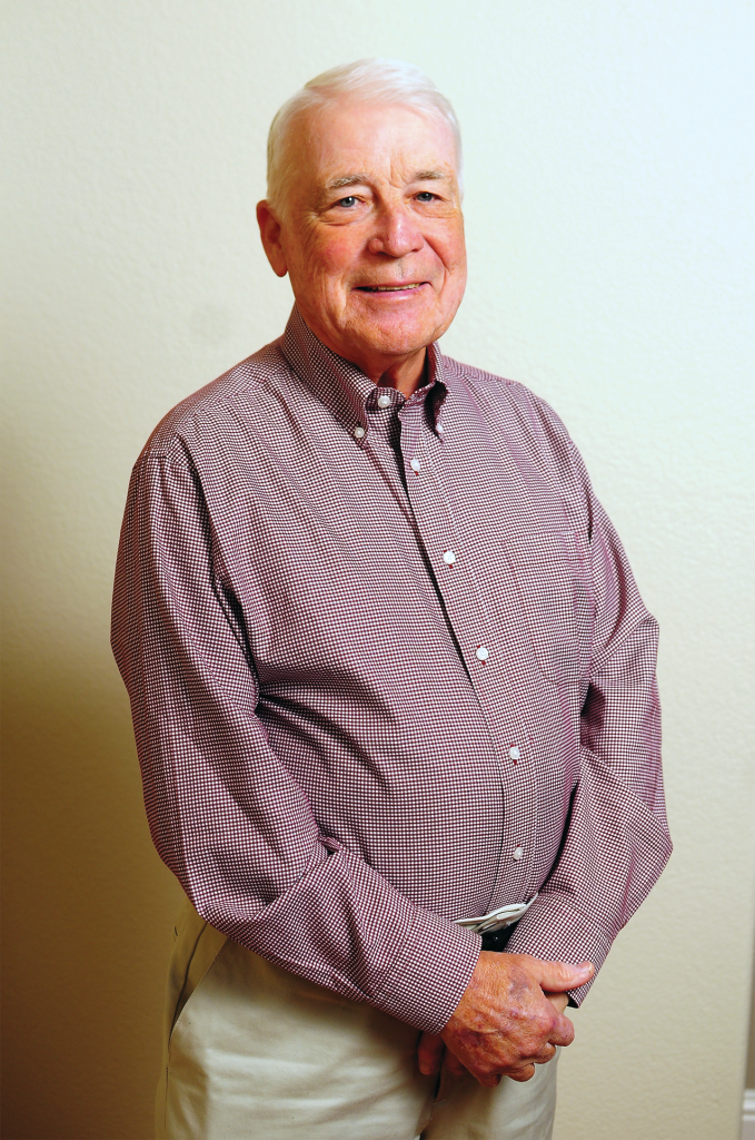 Pat Mead, and elderly mean in a gingham button up shirt, smiles for the camera.