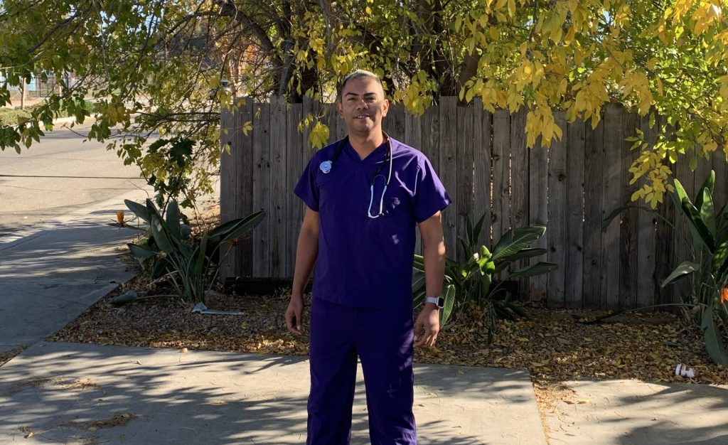 Joao Paulo Democo in purple scrubs standing outside