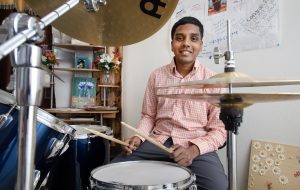 Portrait of Rahul Chintalapudi at home with his drums.