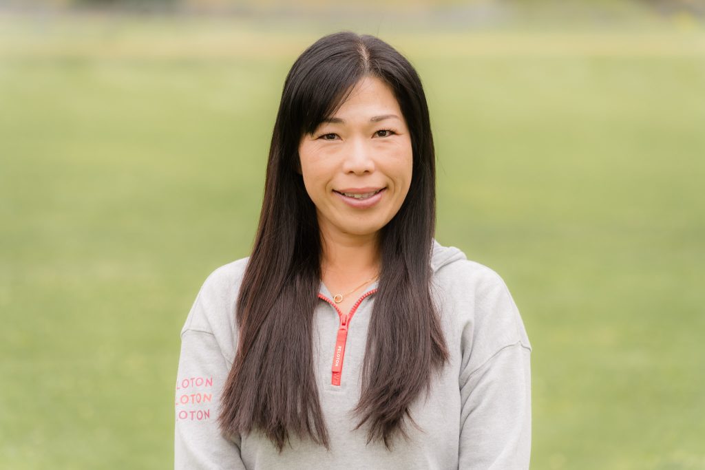 Keiko Inoue, a Japanese woman with long black hair, smiles for the camera on a grassy lawn