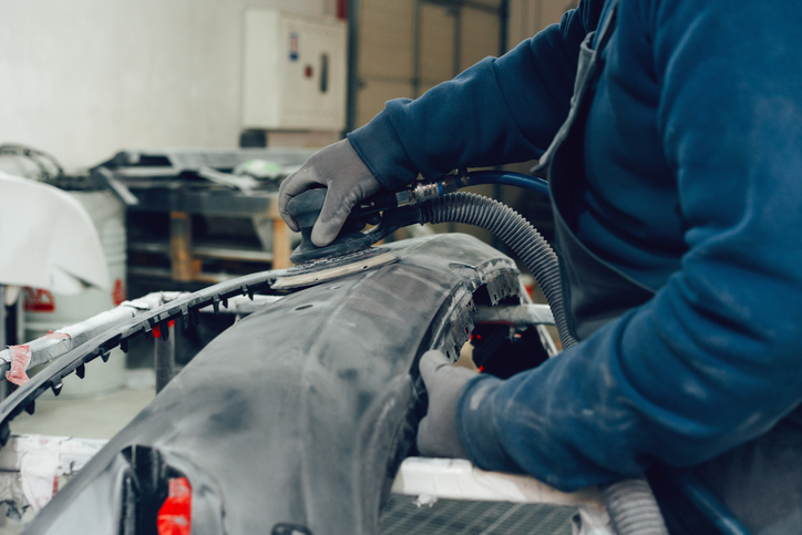 Auto mechanic straightening car body in car service station close up