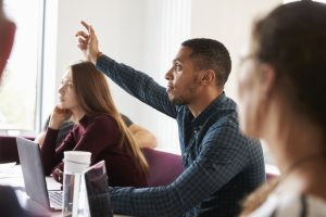 A black man raises his hand in a classroom setting