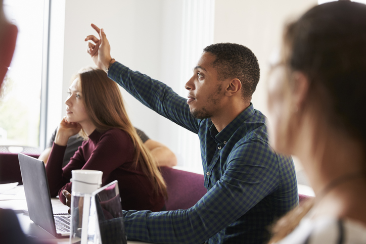 A black man raises his hand in a classroom setting