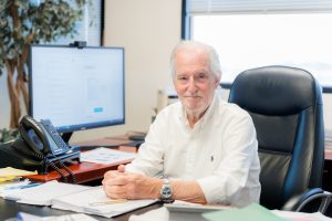 Jan Vogel, sitting at is office desk and smiling for the camera