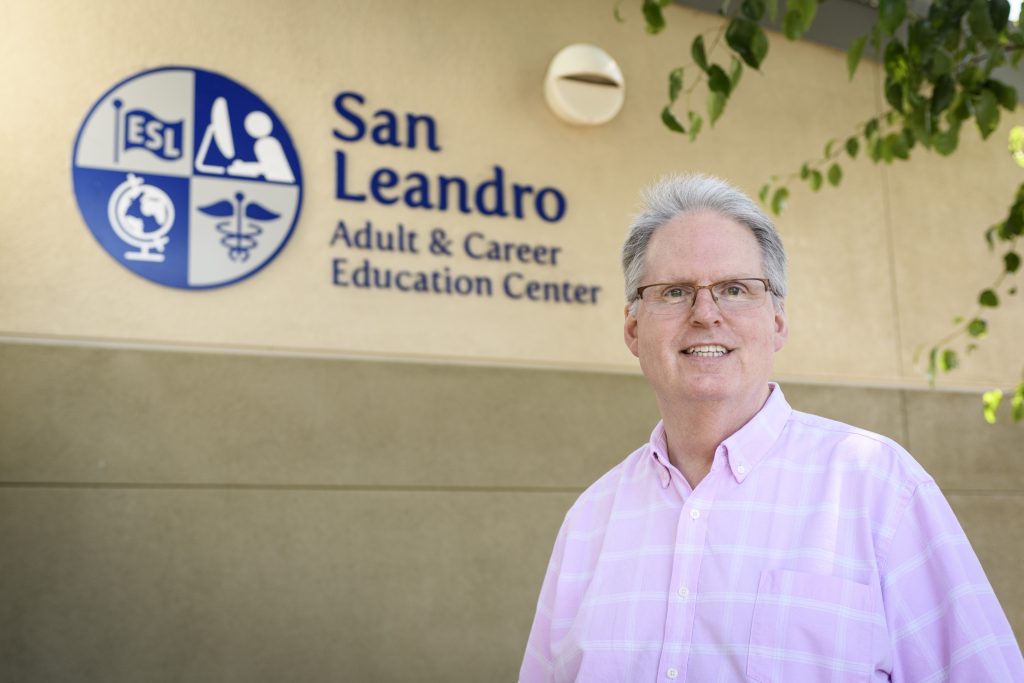 San Leandro Adult and Career Education Center Principal Bradley Frazier standing in front of the education center, smiling for the camera