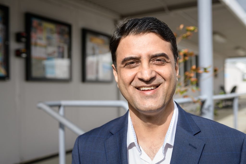 Ahmad Farid Raaid, a man with short dark hair and a blue blazer, smiles for the camera