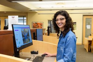 Woman smiling while using a computer at a desk.