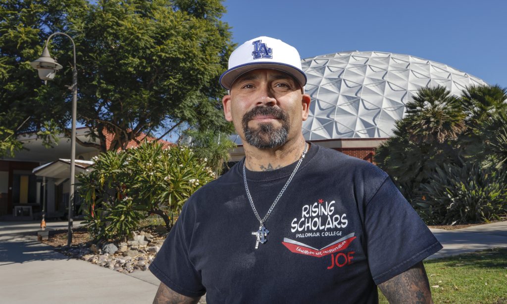 Portrait of formerly incarcerated Jose Romero at Palomar College where he partipates in the Rising Scholars program. He’s also a student at Calfornia State University San Marcos. In the background is the school’s longtime landmark dome that houses the gymnasium.