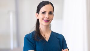 Vanessa Munguia in scrubs standing with her arms crossed and smiling for the camera