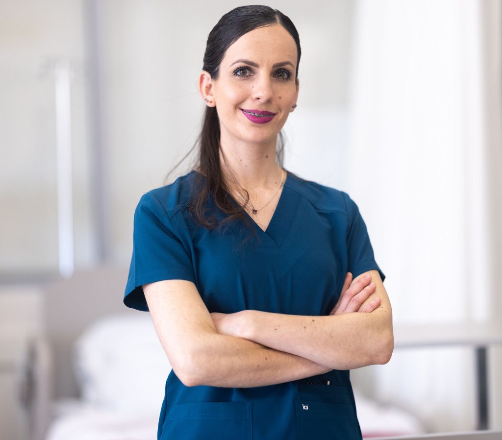 Vanessa Munguia in scrubs standing with her arms crossed and smiling for the camera