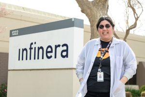 Woman, smiling while standing in front of a sign that says "infinera".