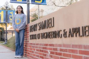 Woman smiling and standing in front of school sign.