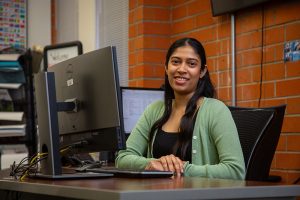 Woman smiling while sitting at desk with a computer.