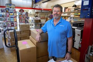 Matt Curto, a man with glasses, greying hair and beard, standing in the PostalAnnex franchise building he owns