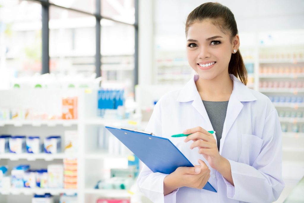 Smiling Asian female pharmacist working in chemist shop or pharmacy