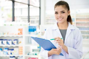 Smiling Asian female pharmacist working in chemist shop or pharmacy