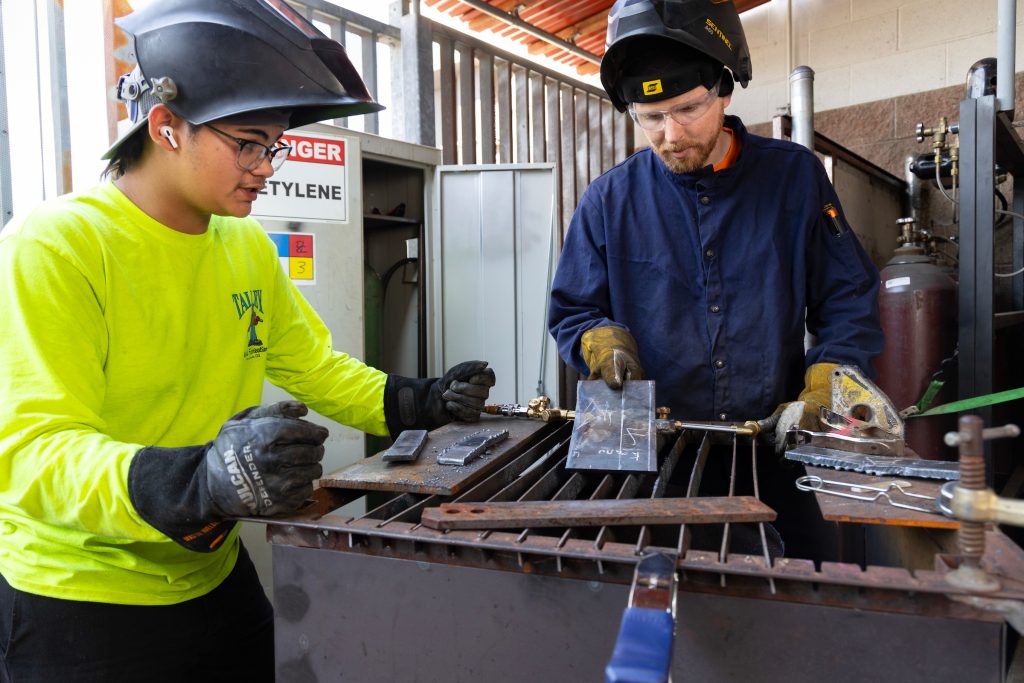 Zachery Cain and a student welding