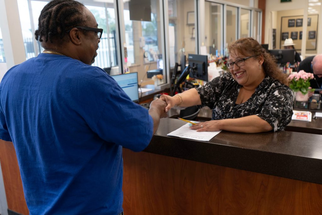 Yolanda Gomez behind a desk helping a man with paperwork