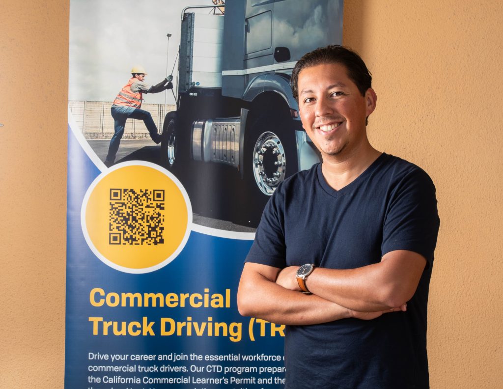 Ricky Bahena Standing in front of a commercial truck driving poster