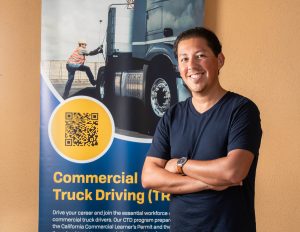 Ricky Bahena Standing in front of a commercial truck driving poster