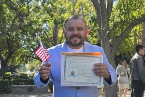 César Omar Cuenca Camacho holding his citizenship certificate and an American Flag