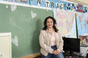 Alma Muñoz standing in front of a classroom chalkboard