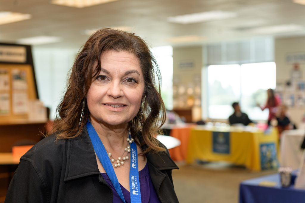 A portrait photo of Nina Scott in a classroom looking towards the camera and smiling