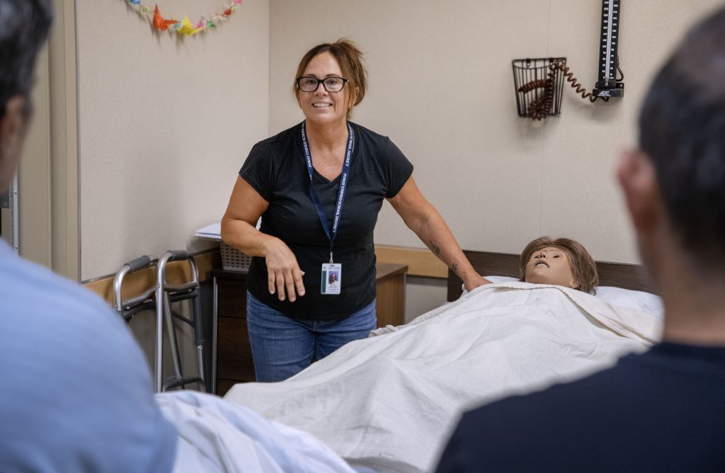 Woman in scrubs training caregriver offerings to students.